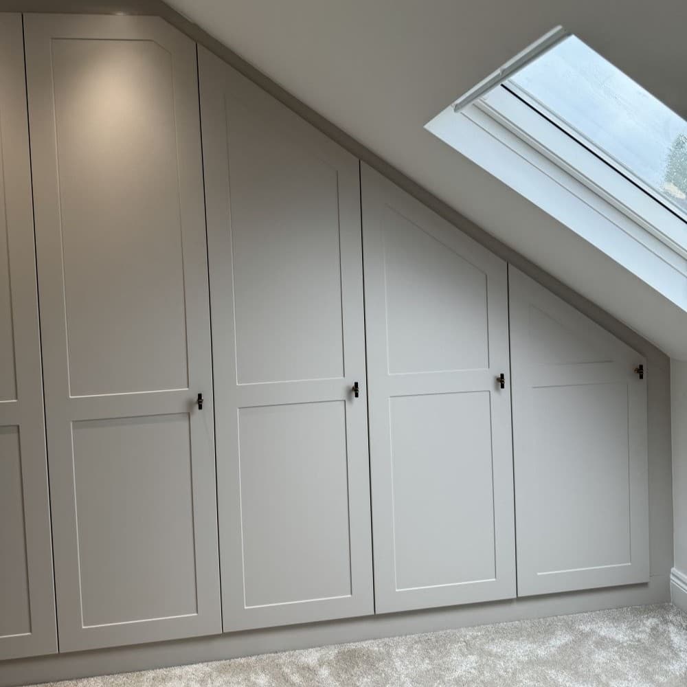 Fitted wardrobe installed under sloped loft ceiling to maximize tricky storage areas