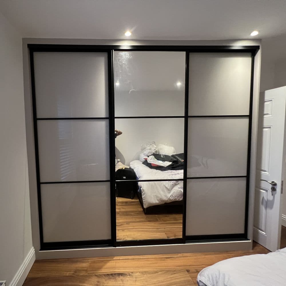 Made to measure wardrobe with sliding doors combining dark wood and mirrored panels
