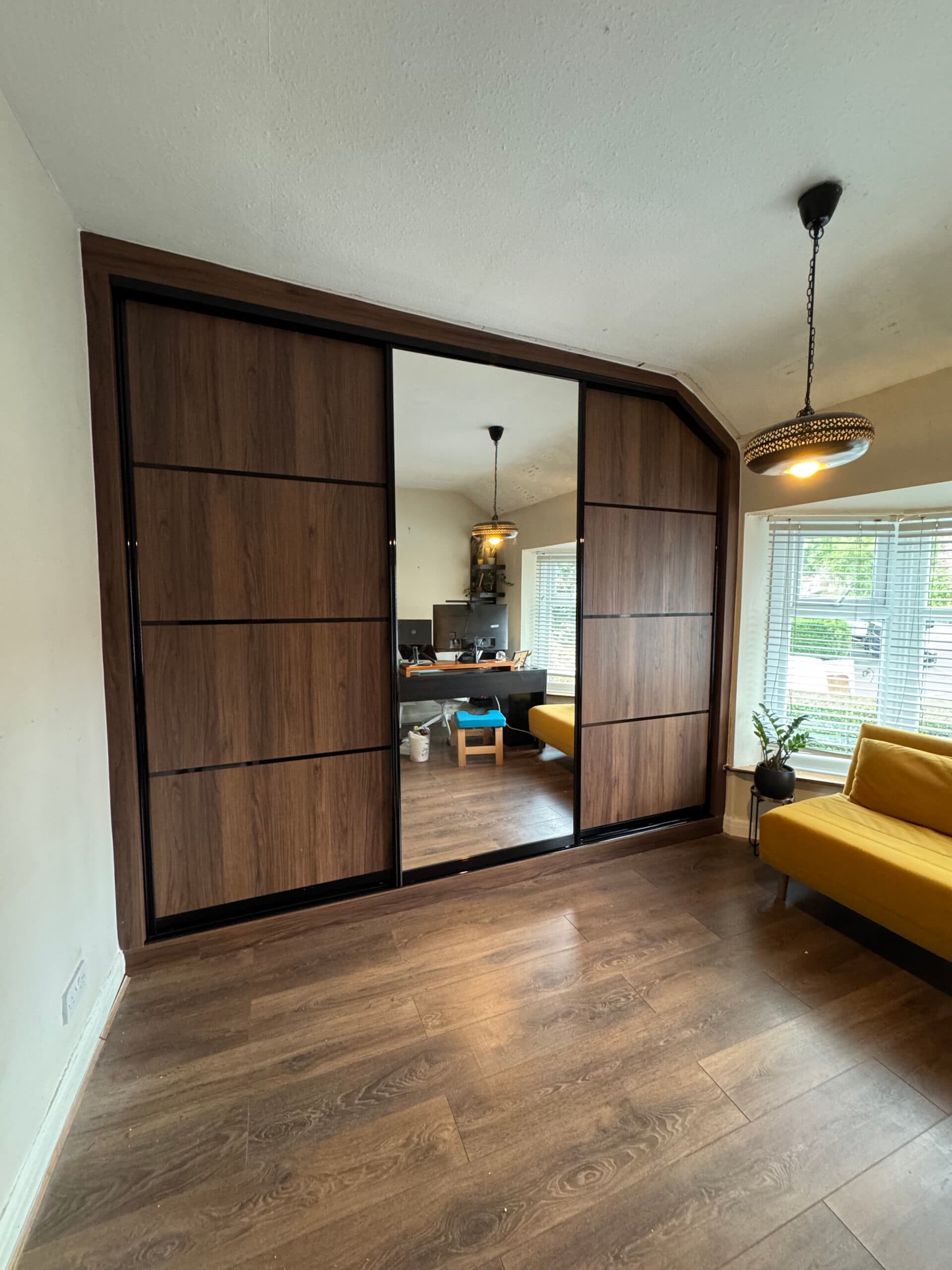 Wooden curved sliding door wardrobe fitted into an open-plan living space.